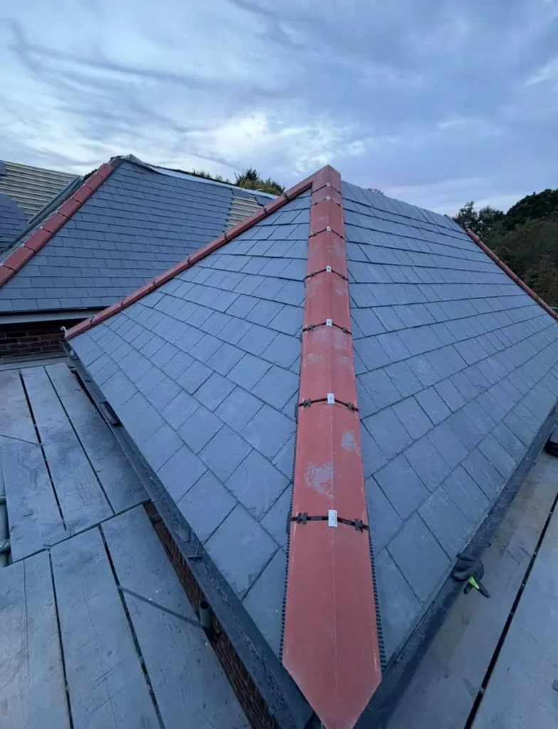 Completed slate roof with red ridge tiles